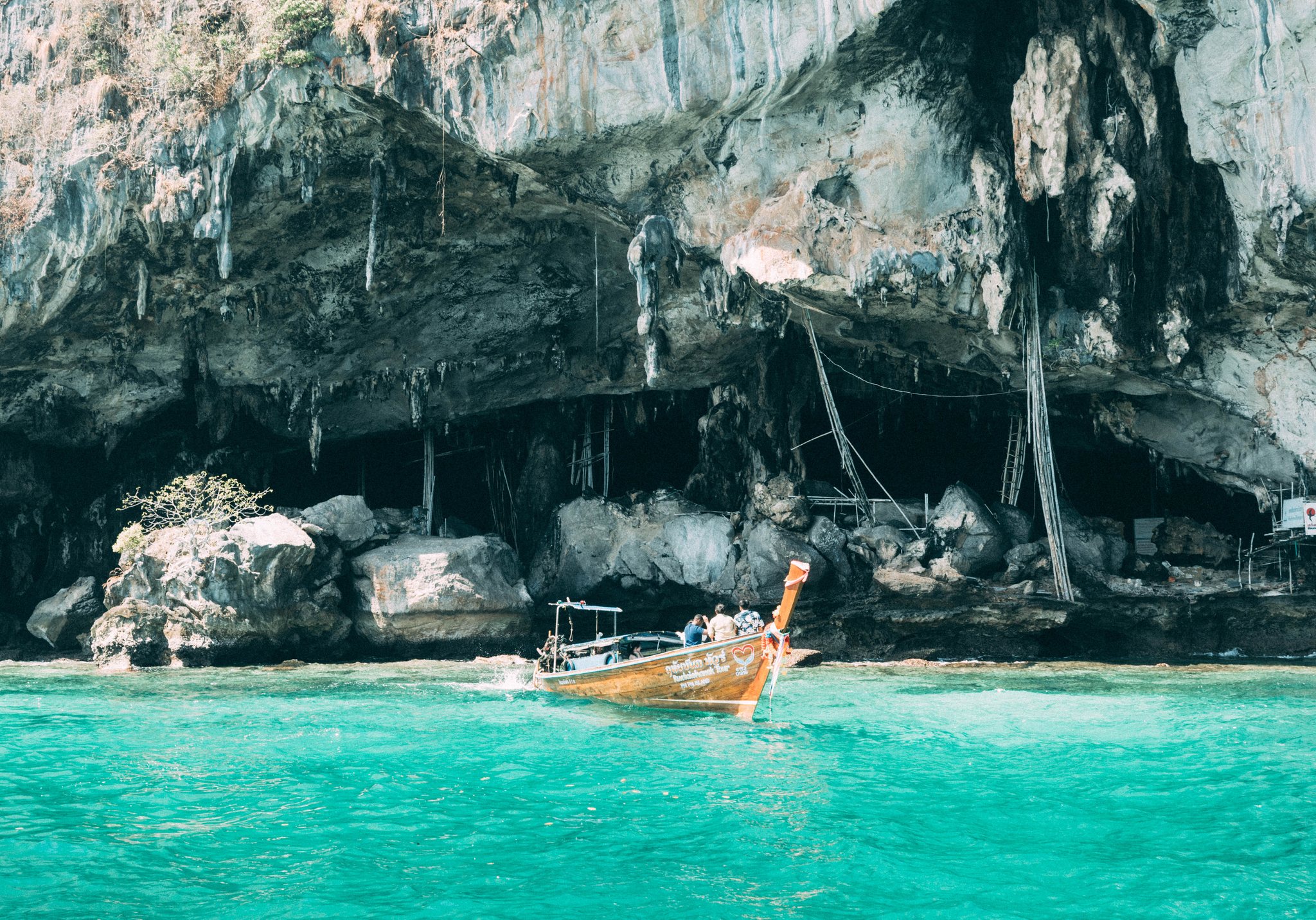 Longtail boat beneath a limestone sea cave