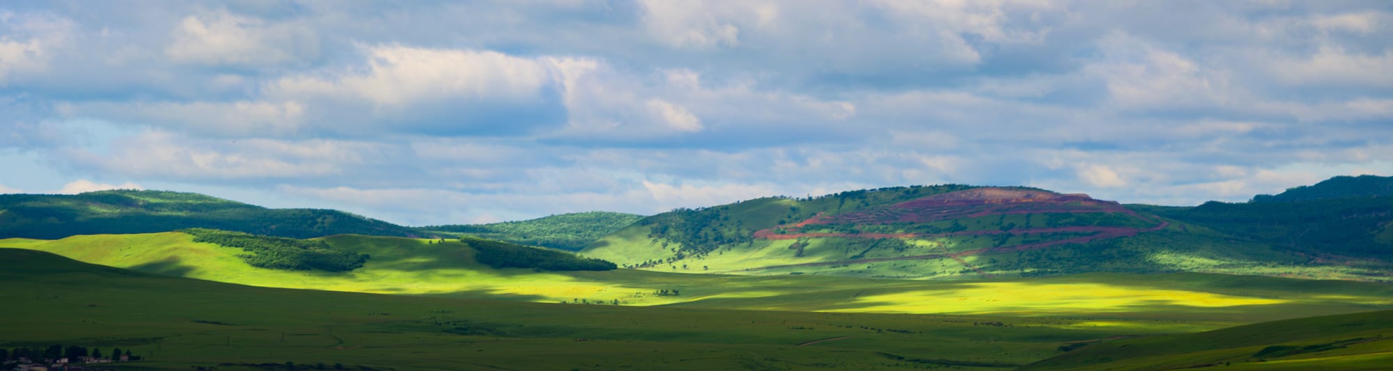 Rolling green grassland under clouds