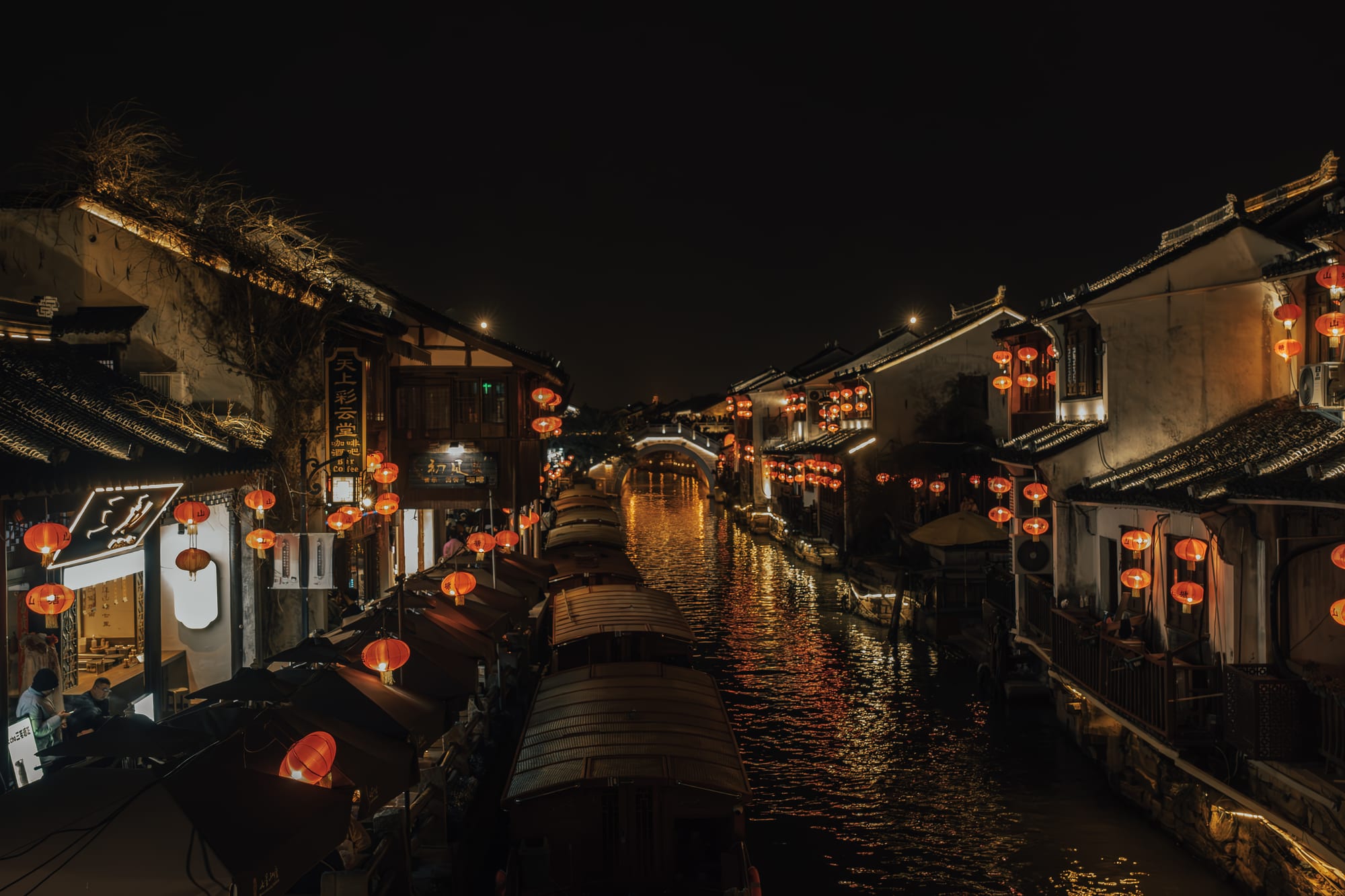 A water town canal after dark with a stone bridge